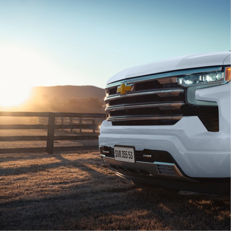 Visão frontal da grade da Chevrolet Silverado em imagem ambientada no campo