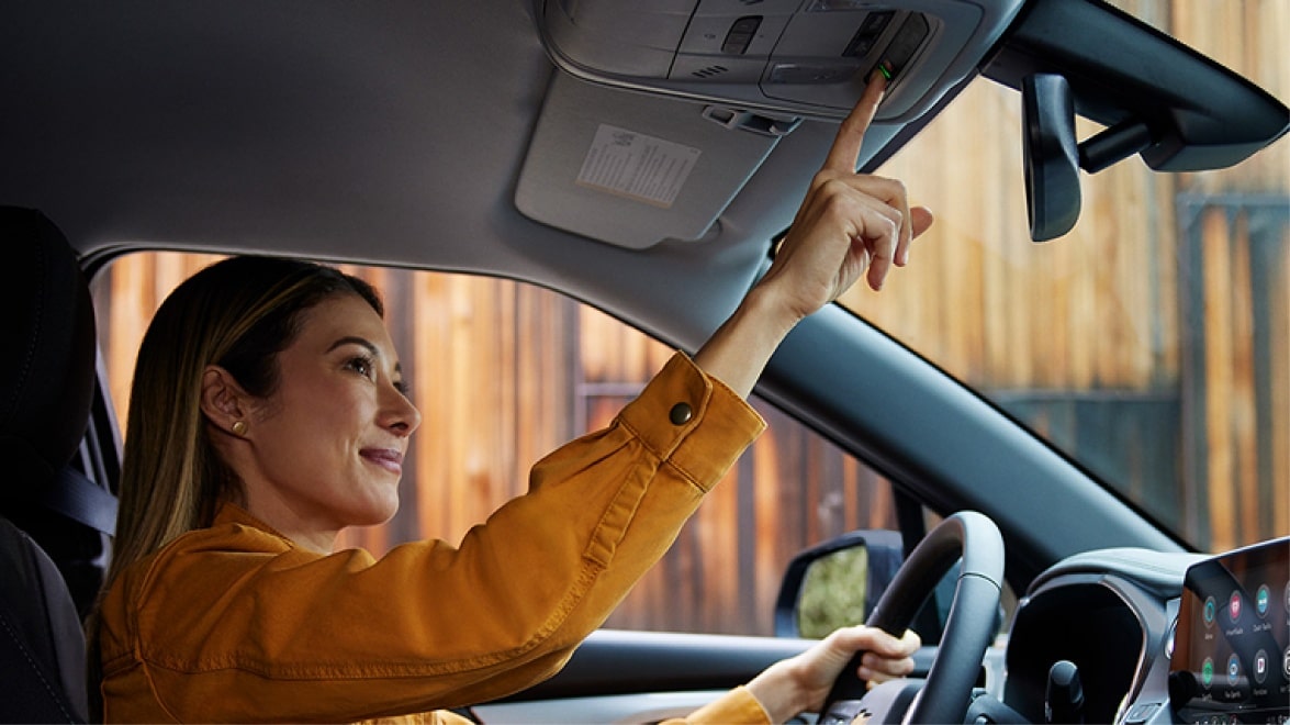 Mulher dentro de uma picape Chevrolet acionando os botões OnStar.