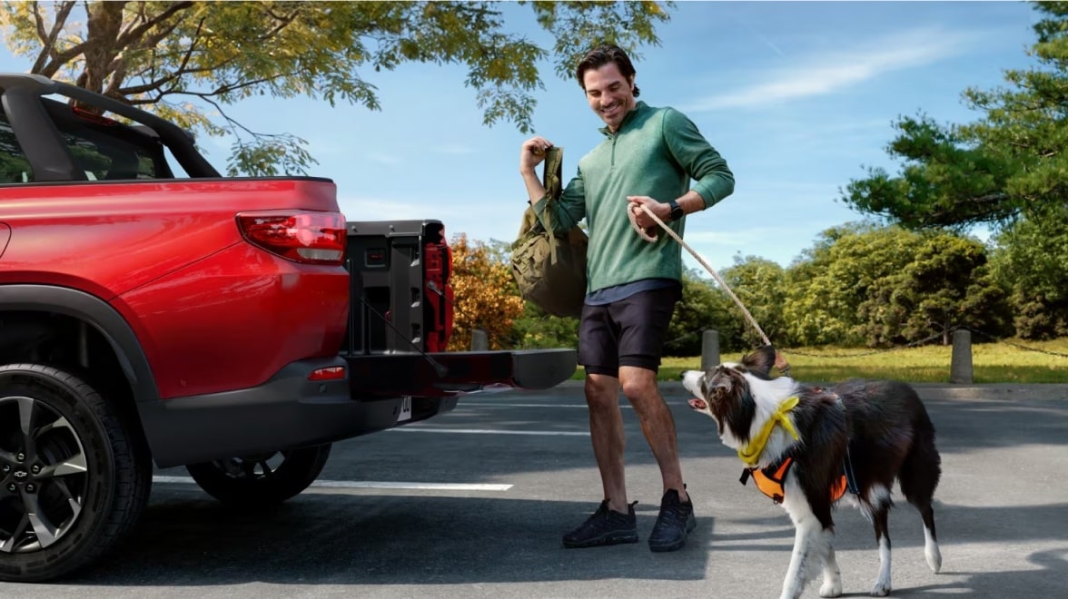 Homem na frente de uma picape Chevrolet segurando o cachorro pela coleira, representando os acessórios de pet da Chevrolet