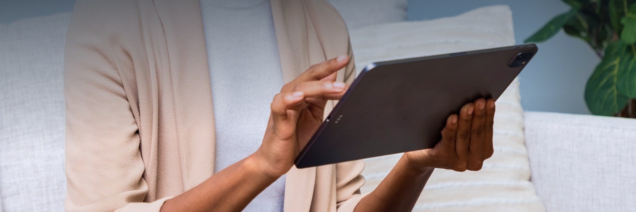 Masthead prodominantemente clara. Uma mulher negra está sentada no sofá mexendo em um tablet. No canto superior esqueredo, o título: Manuais e legislação: Entenda tudo sobre o seu Chevrolet