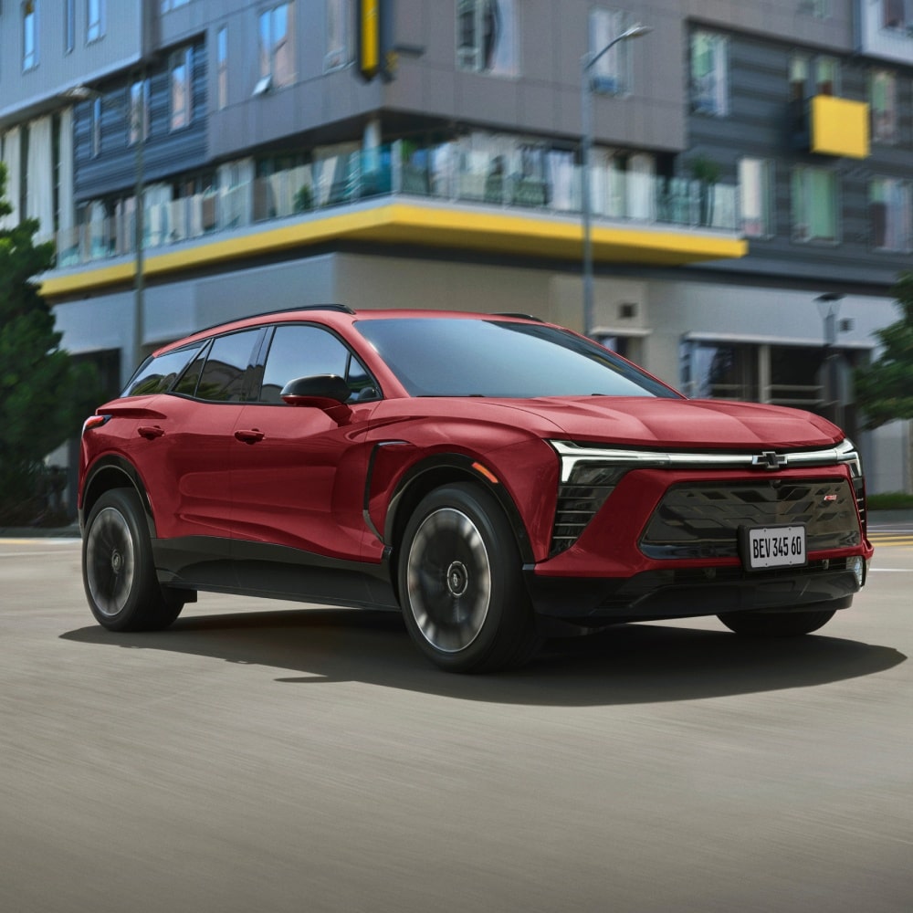 uma blazer EV Vermelha andando em uma rua. Vemos a sua frente e lateral direita.