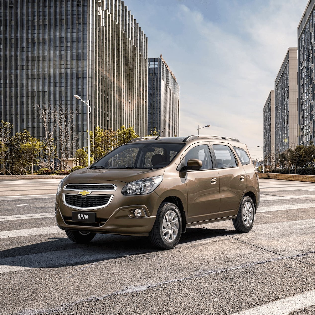 Chevrolet Spin marrom estacionado em rua urbana com prédios ao fundo, referente a recall dos modelos 2013 a 2018.