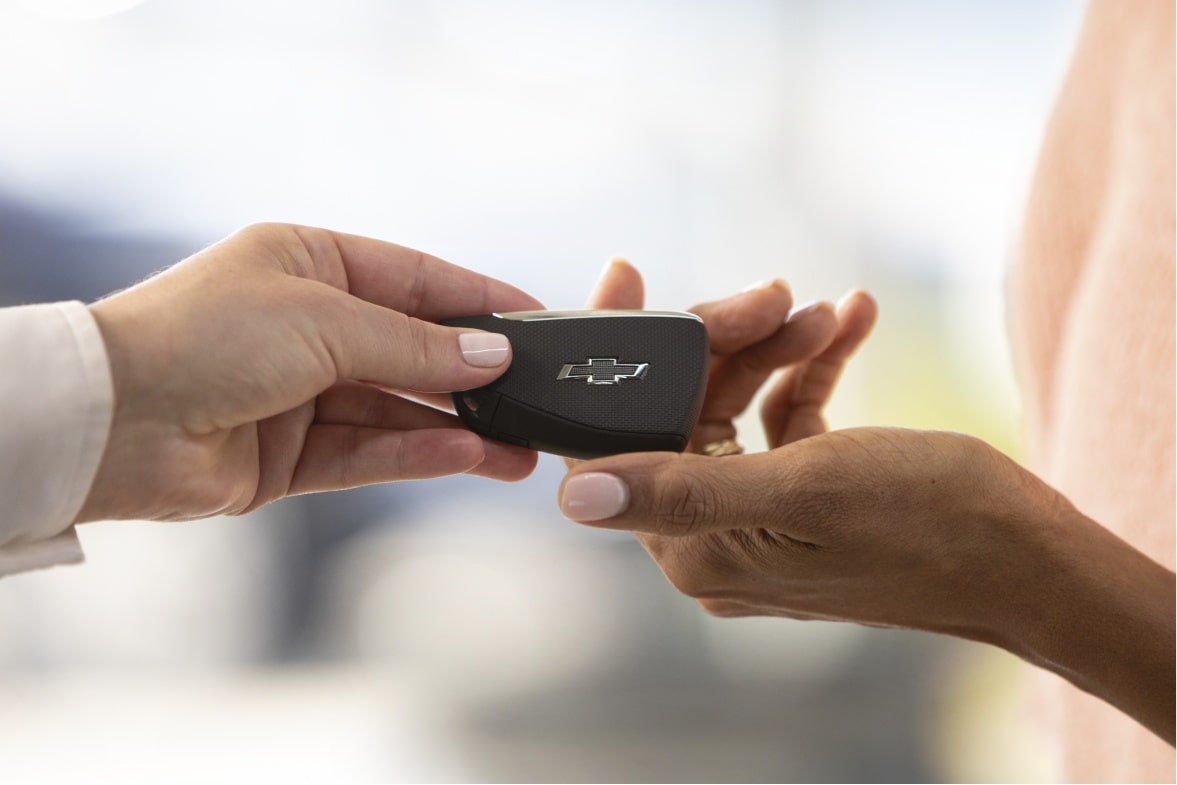 Cliente recebendo chave de veículo Chevrolet em processo de financiamento automotivo GM Financial
