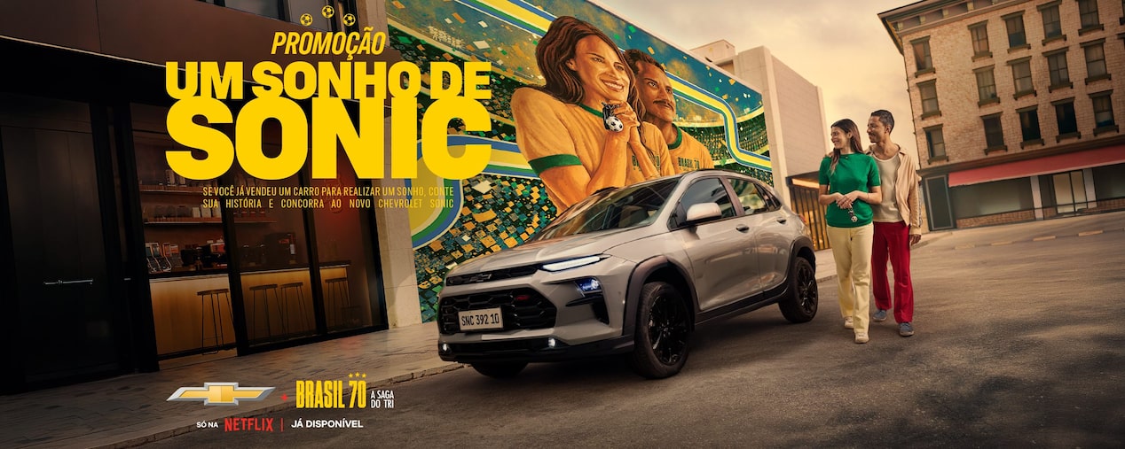 Promoção Chevrolet Sonic Brasil 70 anos, Sonic Suv estacionado em cidade com mural colorido e pessoas caminhando ao lado