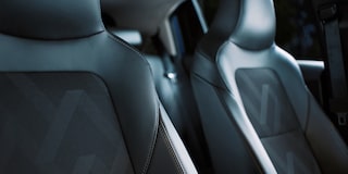 Detalhe dos bancos dianteiros do Chevrolet Onix com acabamento em couro e tecido com costuras aparentes.