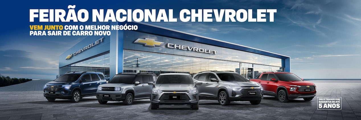 Cinco veículos Chevrolet - Spin, Spark EUV, Onix, Tracker e Montana -  estão estacionados em frente a uma concessionária moderna da Chevrolet, com grandes janelas de vidro e o logotipo da marca.