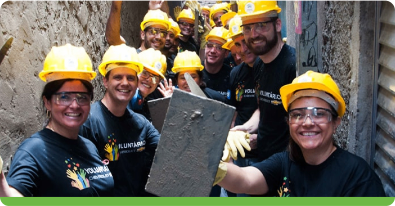 Diversos voluntários com capacete de segurança sorrindo para a foto