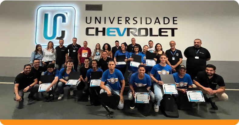 Jovens posando para foto com certificado em mãos na Universidade Chevrolet