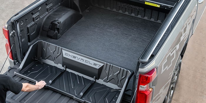 Imagem mostrando caçamba da nova picape Chevrolet Silverado, destacando o acessório "bandeja organizadora". Uma mão de homem toca na bandeja, como se estivesse a desmontando.